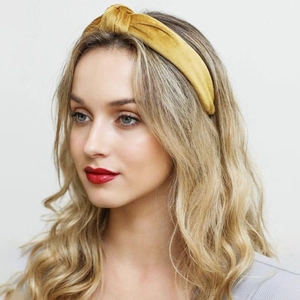 Women's yellow velvet knotted headband accessory shown on a model for a stylish look