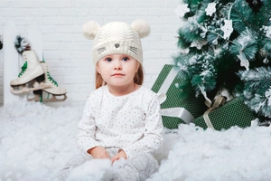 Toddler winter knit hat with cat embroidery and dual pom-poms in a festive Christmas setting