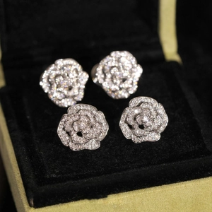 Vue rapprochée de boucles d'oreilles camélia étincelantes en cristaux pavés sur velours
