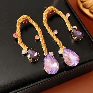 Macro shot of vintage gold woven drop earrings with purple waterdrop crystals