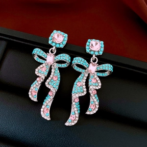 Detail of vintage bow earrings with pink crystal and turquoise beads on black leather