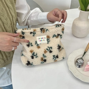 Detail of plush beige cosmetic bag with dark polka dots held in a lifestyle setting