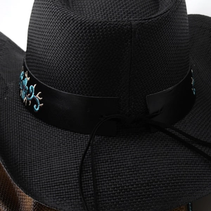 Détail du chapeau de cowboy en paille noire avec broderie florale sur bande en cuir