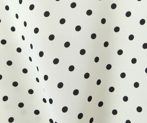 Vista macro de tela blanca con lunares negros y detalle de textura textil fina
