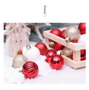 Detail of red and gold Christmas ornaments with glitter and matte textures on pine branches