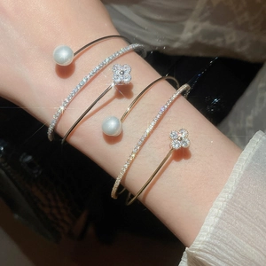 Macro detail of French style zircon flower and pearl layered bracelet set with shimmer