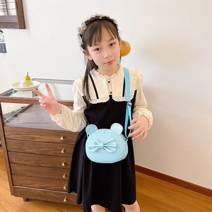 Girl wearing a light blue round crossbody bag with sequin ears and bow detail