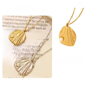 Detailed macro view of geometric shell pendant with pearl on a gold and silver chain