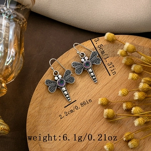 Silver dragonfly drop earring with iridescent gemstone and dimensions on wood tray