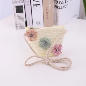 Detail of cream woven straw bag for girls featuring three 3D floral mesh decorations