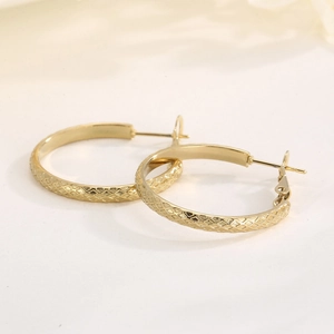 Detailed view of gold plated stainless steel hoop earrings with diamond pattern texture