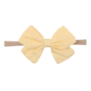 Close-up of soft nylon baby headband with a yellow dotted bow and ribbed fabric detail
