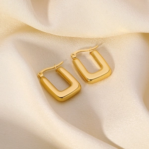 Polished 18K gold rectangular stainless steel hoop earrings on beige silk background
