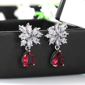 Detailed macro view of pear-cut red zircon drop earrings with marquise floral stone accents