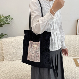 Détail du sac cabas en velours noir avec écusson en dentelle florale et fines bandoulières
