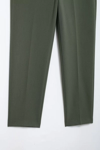 Détail du pantalon habillé vert olive avec pli marqué et texture de tissu lisse