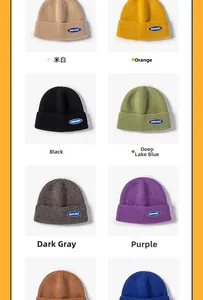 Detail showing various colors of thick knitted beanies with a blue lettered logo patch