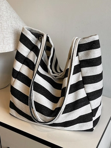 Large capacity black and white striped canvas tote bag with double shoulder straps on white table