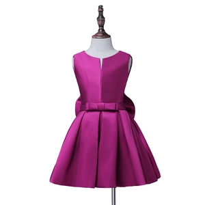 Detail of fuchsia satin girl's dress with waist bow and pleated sleeveless design