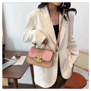 Detail of the pink herringbone fabric and gold V-shaped buckle on a square handbag