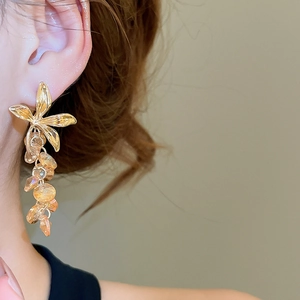 Détail de boucles d'oreilles fleur en cristal champagne avec franges ambrées sur modèle