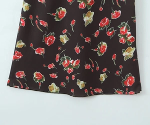 Detailaufnahme des floralen Prints auf schwarzem Stoff mit roten Blumen und Blättern