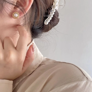 Detail of sweet 925 silver pearl earring and hair clip worn by a model in soft light