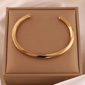 Polished gold Mobius bangle displayed in a beige silk-lined luxury jewelry box