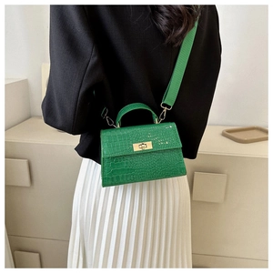 Detail of green crocodile textured mini bag with gold twist lock and woven strap