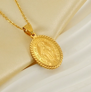 Close-up of Virgin Mary gold oval pendant with textured rope edge on silk fabric