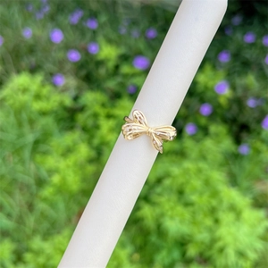 Elegant 18K gold plated bow ring with zircon stones on a white pedestal display