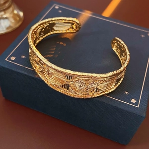 Close-up of 18k gold plated open cuff with intricate woven texture and vintage pattern