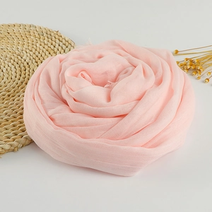 Detail of light pink soft cotton linen scarf with frayed edges in a rose fold