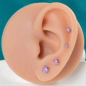 Detail view of four pink opal cartilage studs with four-prong settings on a model ear
