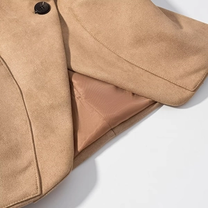 Detailed close-up of camel suede jacket with fine stitching and black button