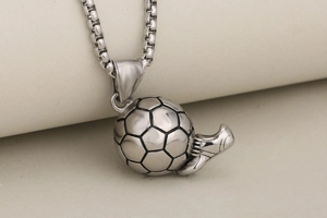 Close-up of silver soccer ball and football boot pendants on a box chain necklace