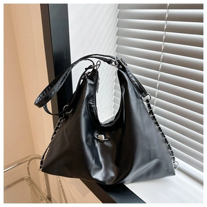 Close-up of black PU tote with silver metal ball detail and chain straps on windowsill