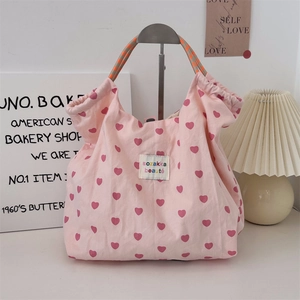 Detailed view of pink canvas tote with red heart patterns and woven rope handles