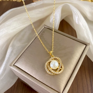 Elegant gold necklace with interlocking zircon rings and white pearl on jewelry box