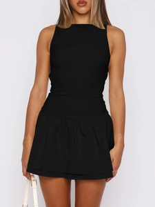 Detail of elegant black sleeveless low waist mini dress with pleated hem and white bag