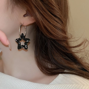 Close-up of black sparkly star pendant hoop earrings on model for a trendy punk hip-hop look