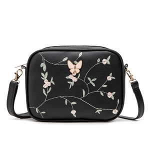 Black camera crossbody bag featuring floral embroidery and a 3D butterfly clasp detail