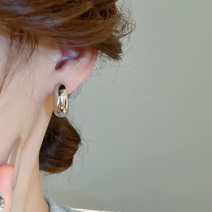 Dettaglio di un ear cuff a goccia in argento minimalista con finitura lucida a specchio
