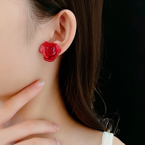 Gros plan de boucles d'oreilles roses rouges en résine portées montrant l'éclat poli