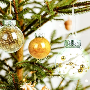 Detail of elegant gold and transparent Christmas baubles with beads hanging on a pine tree