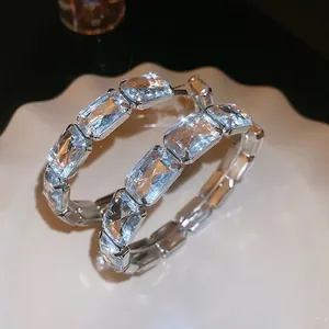 Silver square-cut emerald cubic zirconia hoop earrings on a decorative white plate