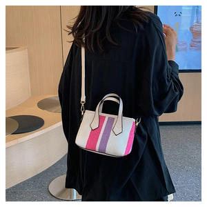 Detail of striped canvas mini bag with leather trim on model in a cafe setting