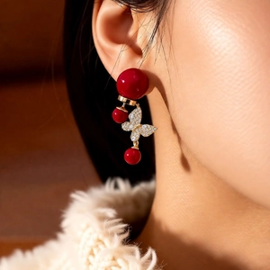 Vue macro de boucles d'oreilles papillon plaquées or 18k avec perles rouges et cristaux