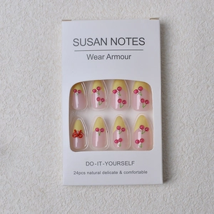 Detail of pink almond fake nails with 3D cherry accents and red bow designs in a 24pc set