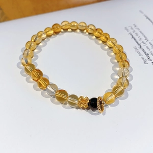 Detail of beaded bracelet with citrine stones and gold clover charm on magazine background